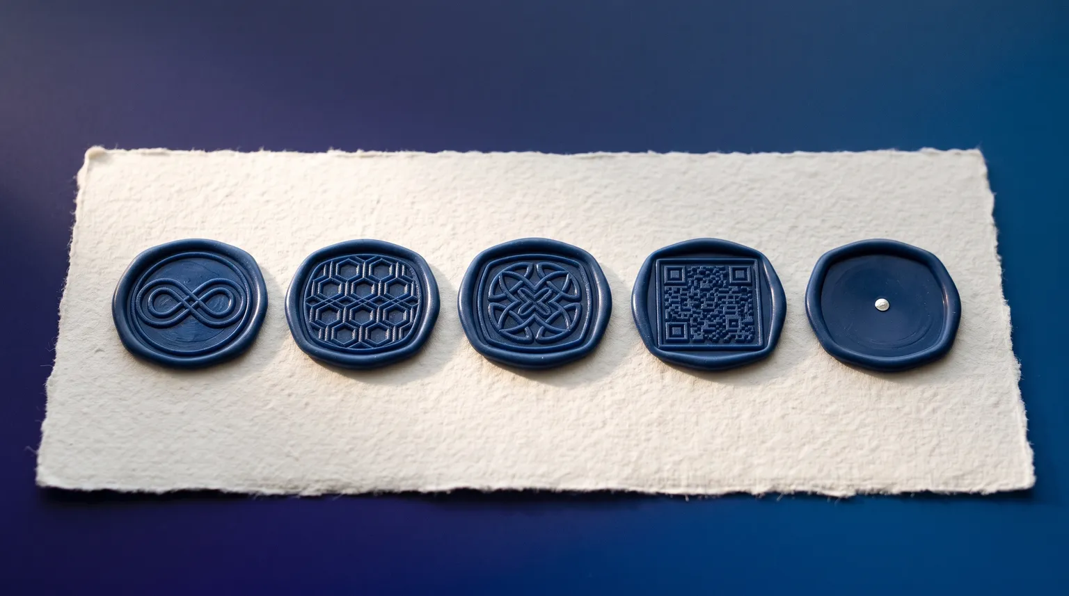 Five deep blue wax seals in a row on heavy off-white paper, four pressed with a pattern and the last one still blank.