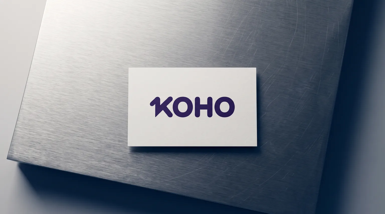 The KOHO logo on a plain white card resting on a slab of brushed stainless steel.