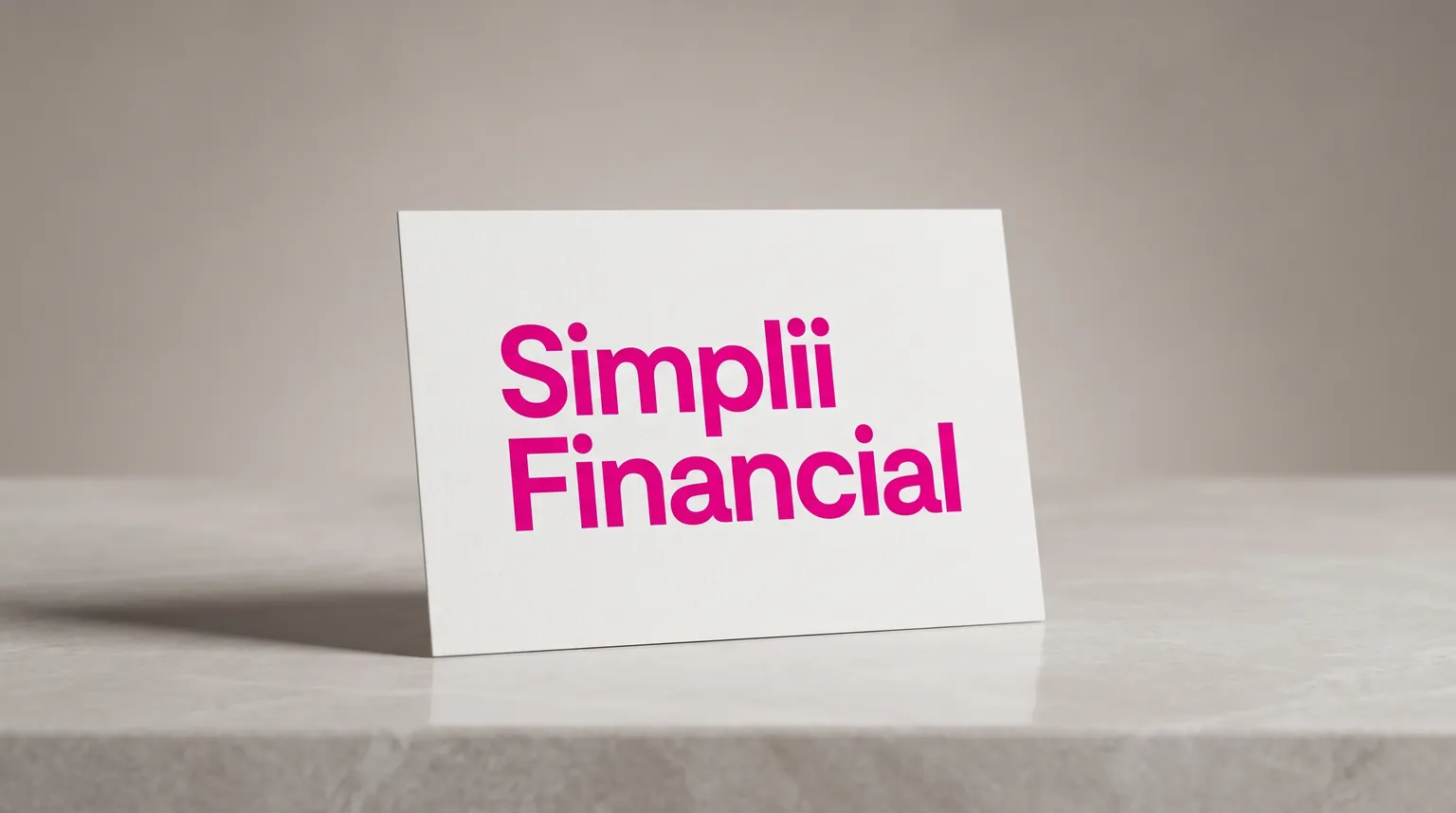 The Simplii Financial logo on a matte white card standing on a pale grey stone surface under soft studio light.
