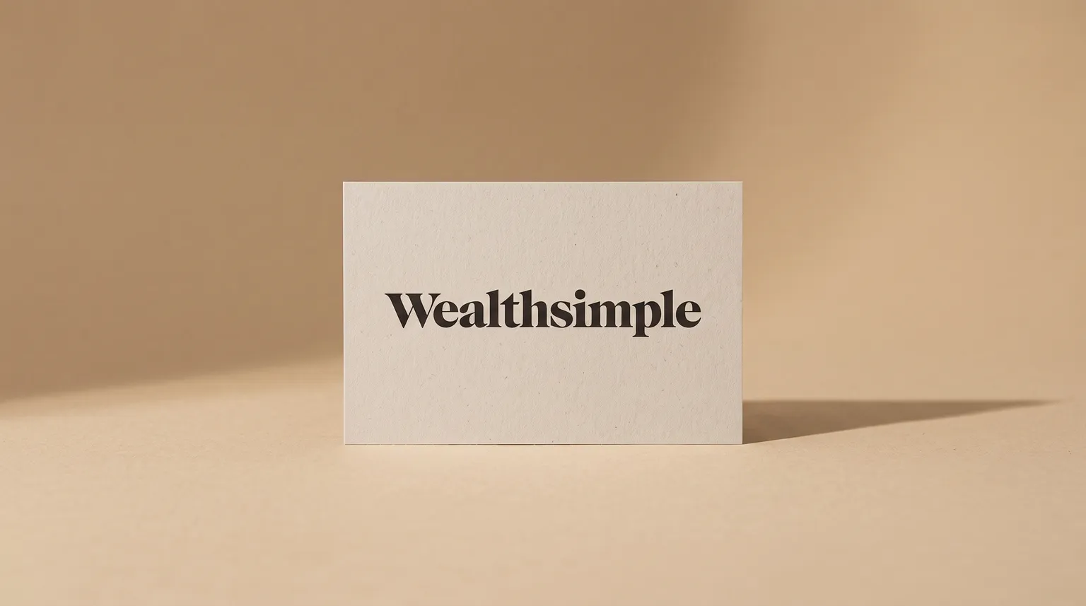 The Wealthsimple logo on a matte card standing upright against a warm sand-coloured studio backdrop.